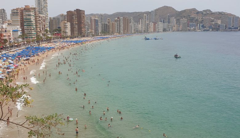 Crowded Levante beach in Benidorm under a July sun, skyline behind