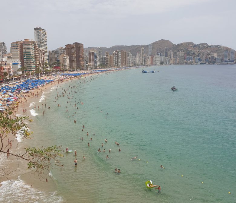 Crowded Levante beach in Benidorm under a July sun, skyline behind