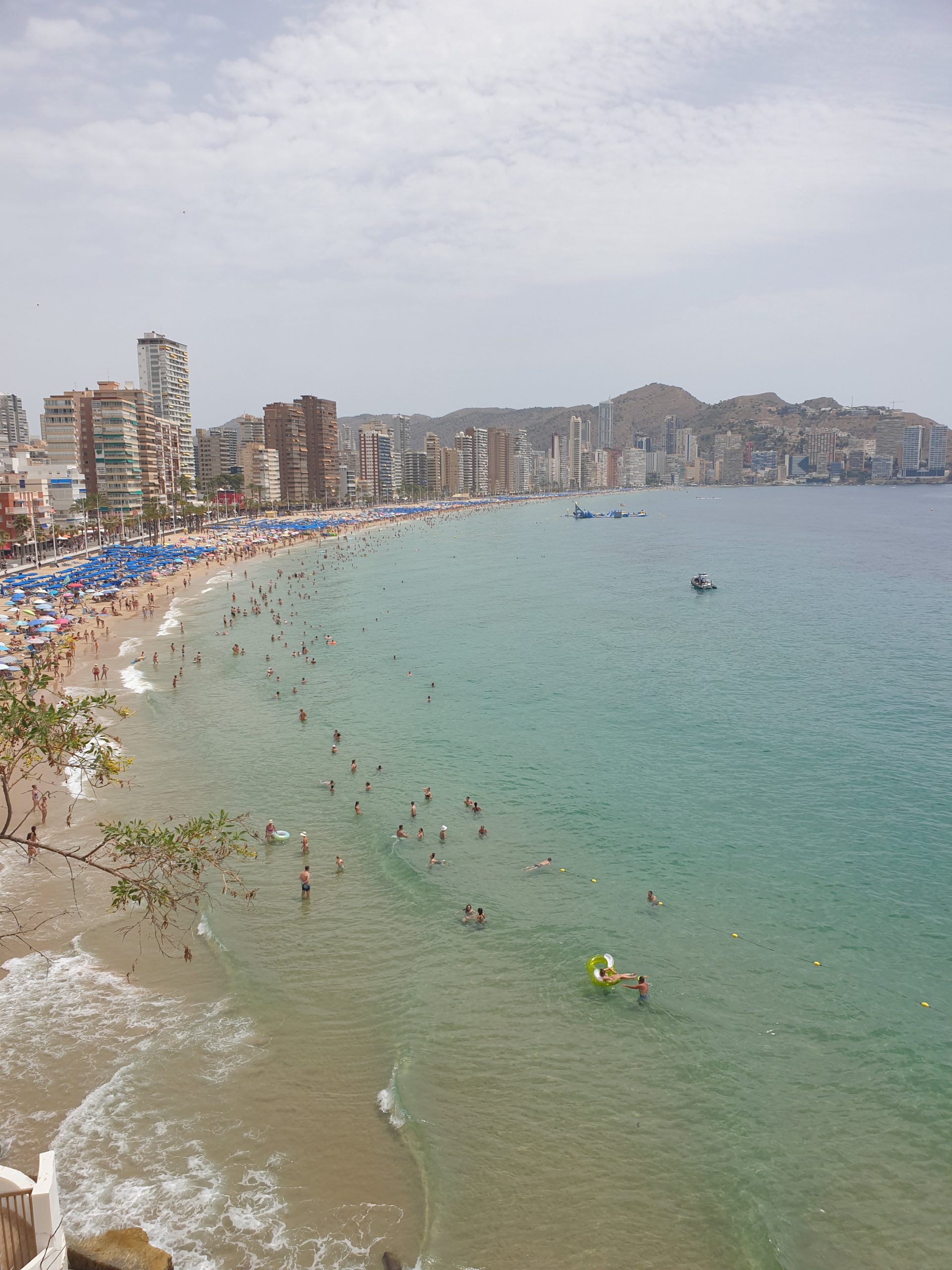 Crowded Levante beach in Benidorm under a July sun, skyline behind
