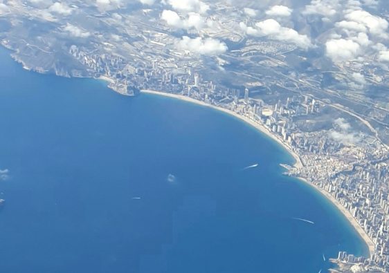 Benidorm bay photographed from an aircraft window, showing both beaches, the high-rise skyline and Benidorm Island