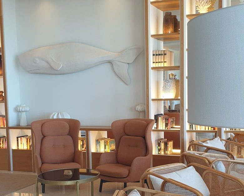 The lounge at the H10 Porto Poniente in Benidorm, with a white whale sculpture above backlit bookshelves