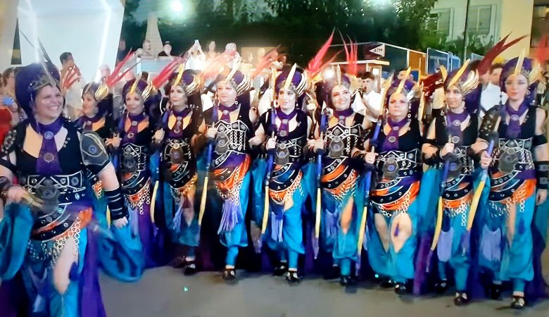 A filà in teal and purple costume marching in the Moros y Cristianos parade in Benidorm
