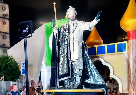 A Moorish king in silver robes on a float at the Moros y Cristianos parade in Benidorm at night